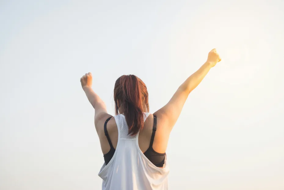 femme heureuse qui lève les mains au ciel avant de partir seule en vacances